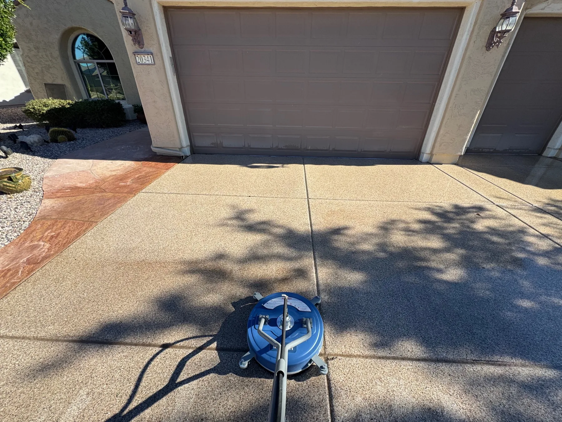 Residential driveway cleaning in progress with a surface cleaner